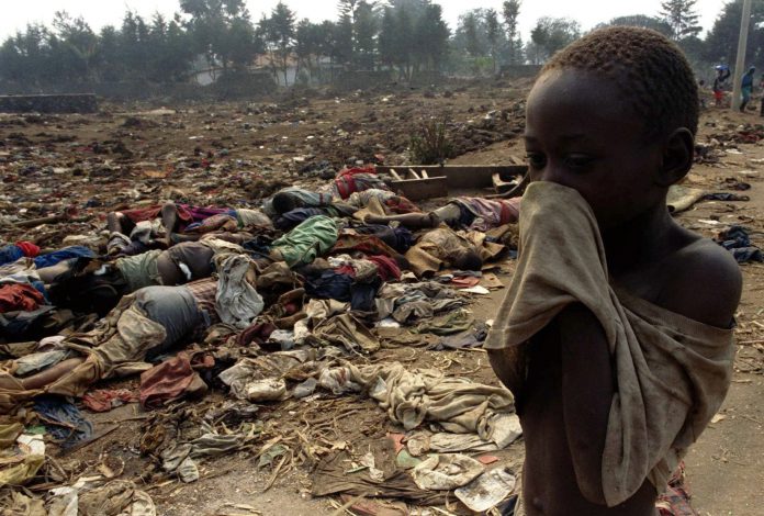 File photo of a Rwandan boy covering his face from the stench of dead bodies